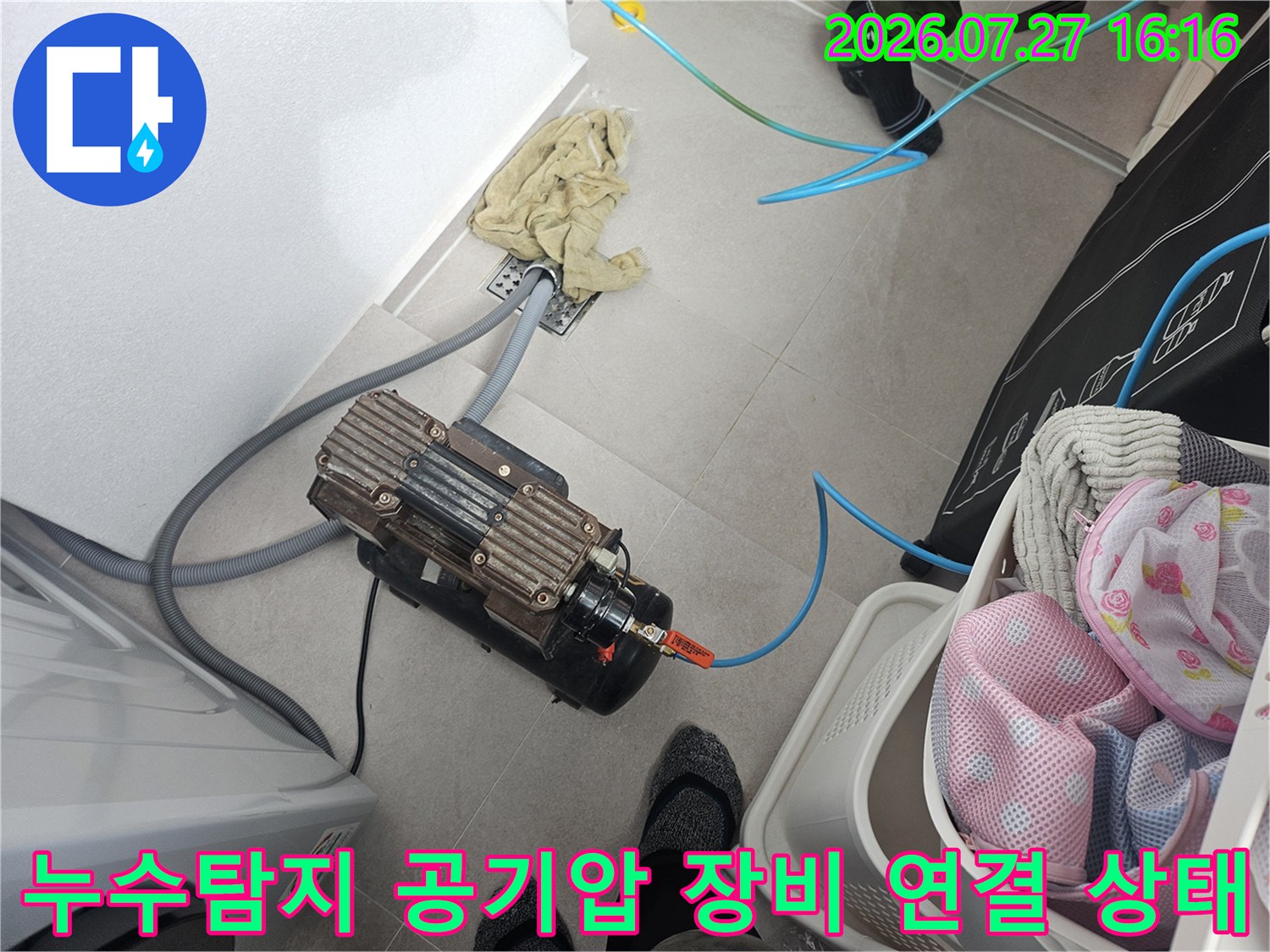바닥에 놓인 전문 누수 탐지용 공기 압축기와 파란색 호스-연결 모습