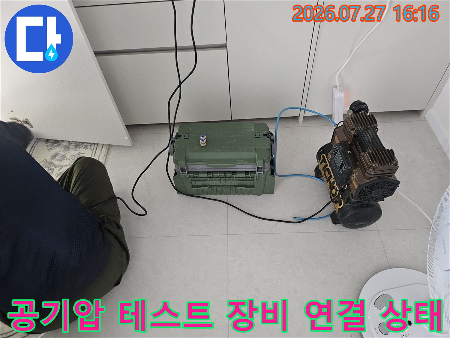 전원선과 호스가 연결된 공기 압축기와 제어 박스-누수 탐지 작업 중