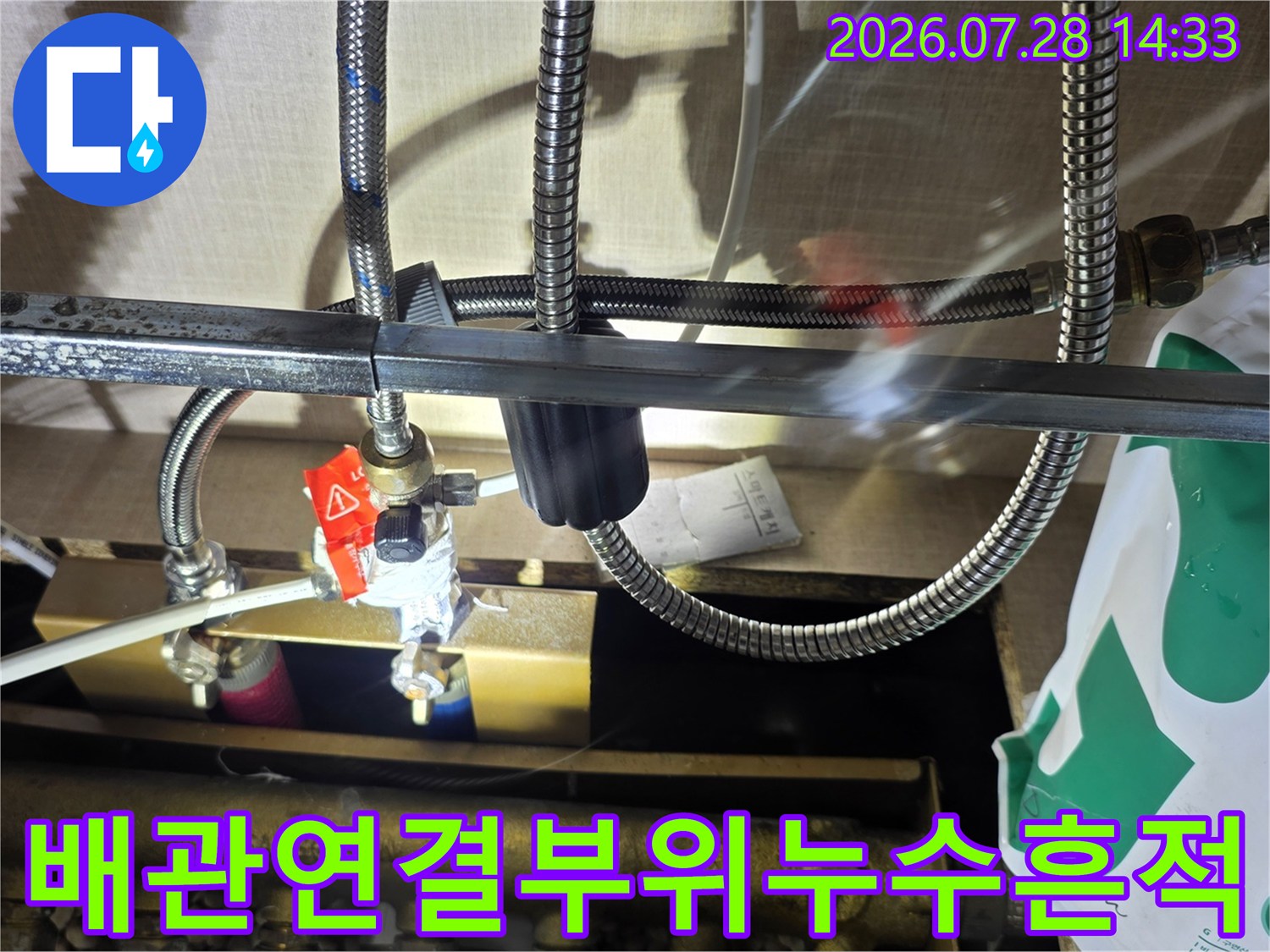싱크대 아래 분배기 연결 너트 주변에 물기가 맺혀 있는 사진