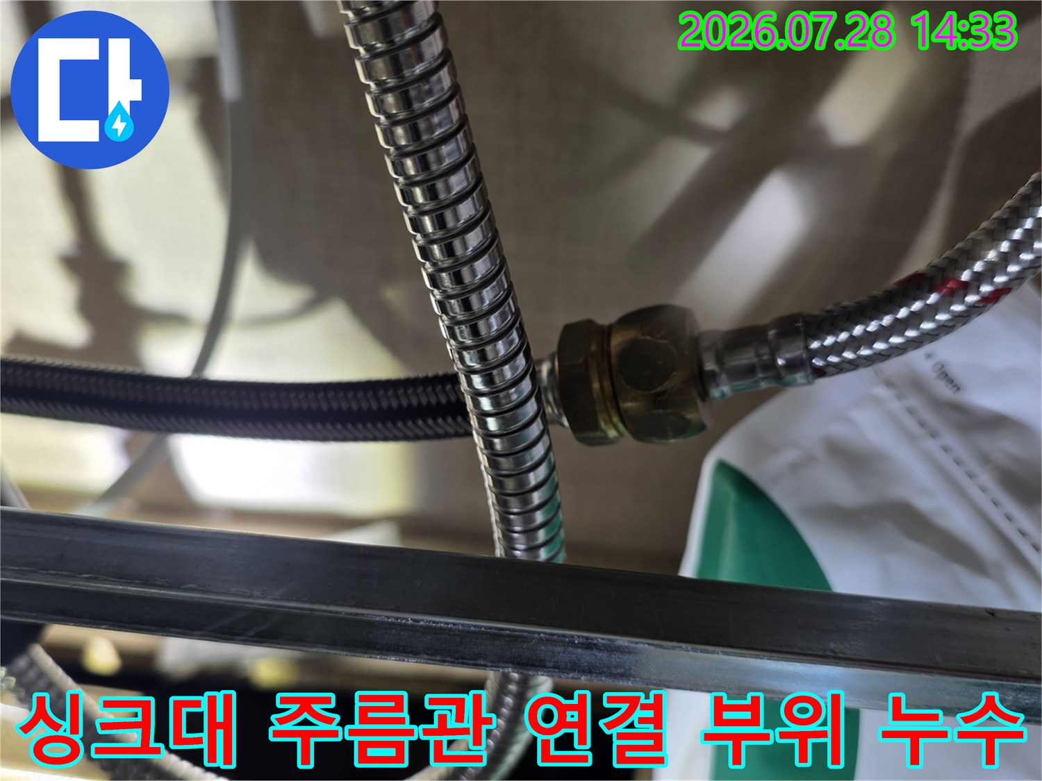싱크대 하부의 스테인리스 주름관과 연결 너트 부분에서 물이 비치는 모습