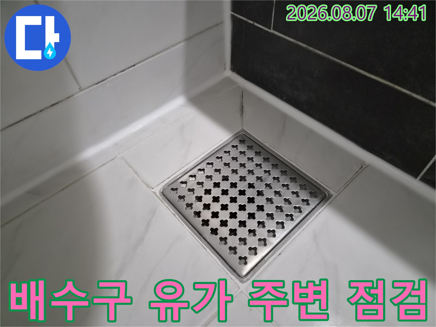 스테인리스 배수구와 인접한 타일의 줄눈 상태를 근접 촬영한 이미지입니다.