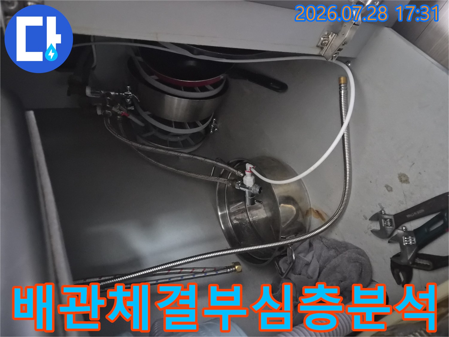 싱크대 하부의 식기세척기 관련 배관과 호스 연결부를 정밀하게 점검하는 장면