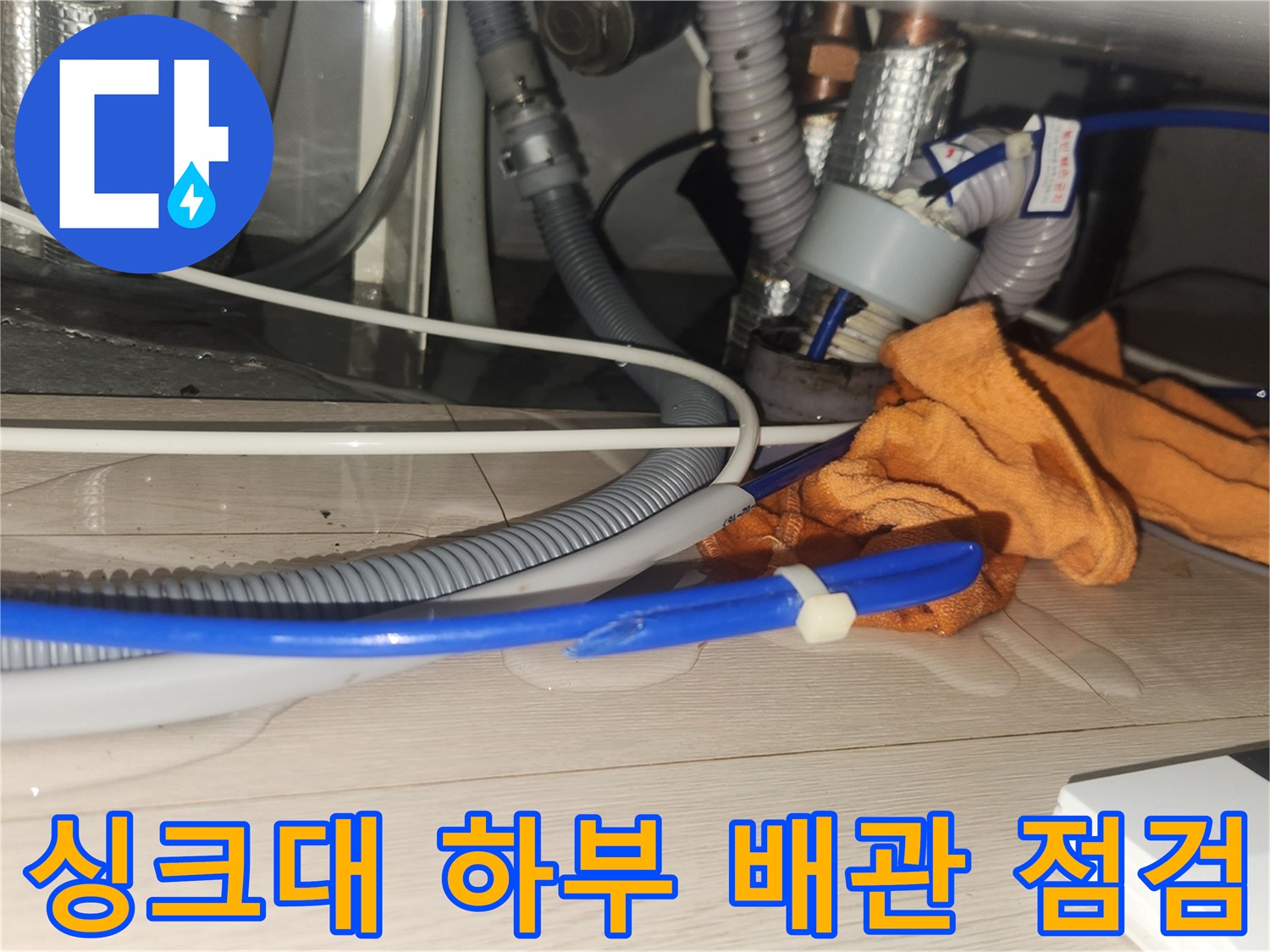 분당 싱크대 하부의 복잡한 배관 연결 부위와 작업용 장갑 모습
