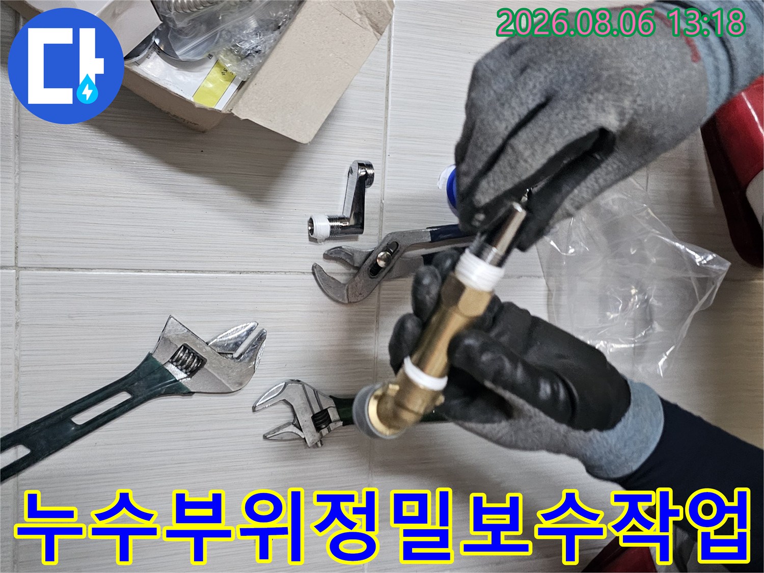 장갑을 낀 손으로 수전 연결용 황동 파이프를 고정하는 공사 현장 사진