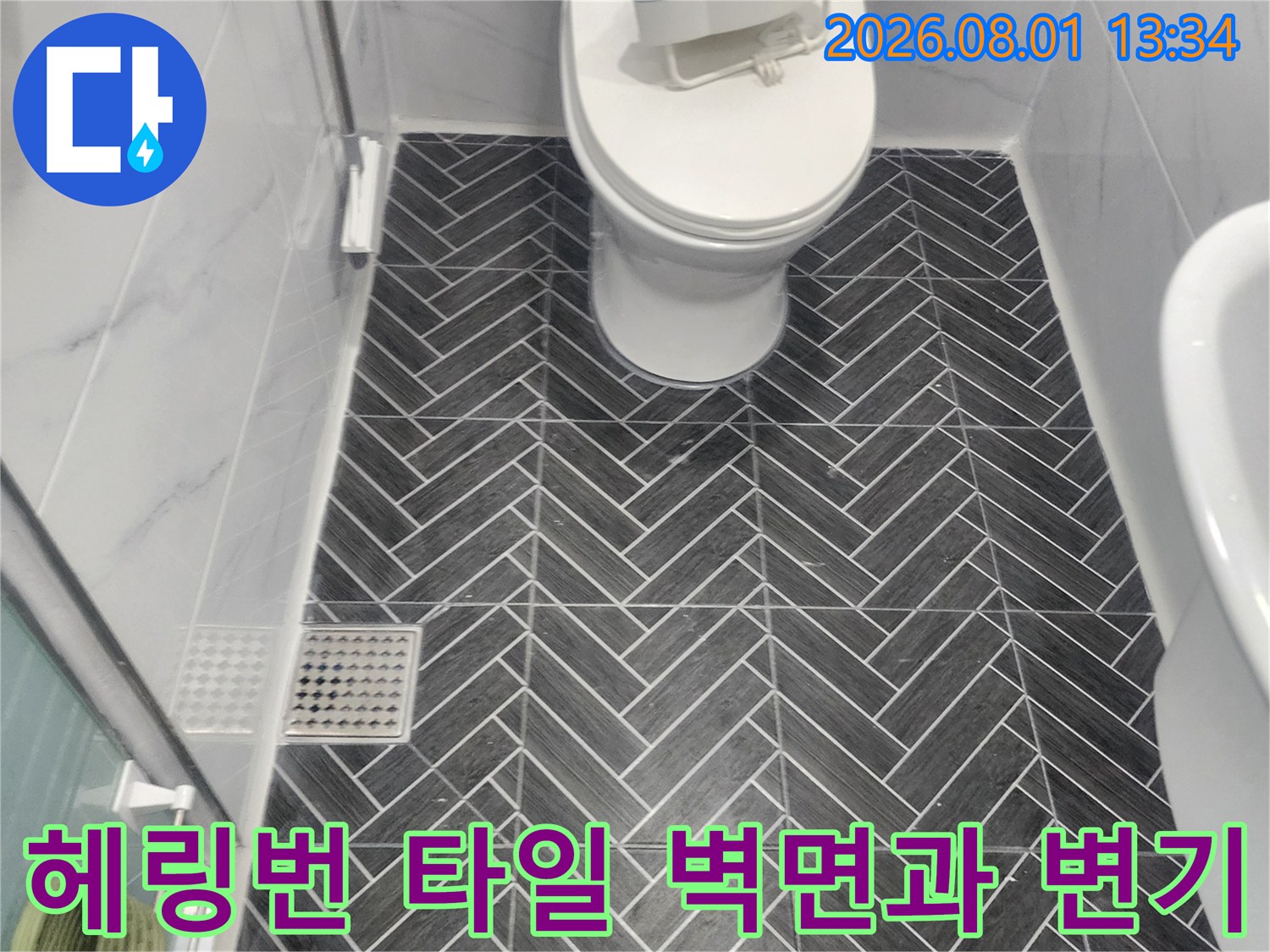 회색 계열의 헤링번 패턴 타일이 시공된 화장실 내부 전경