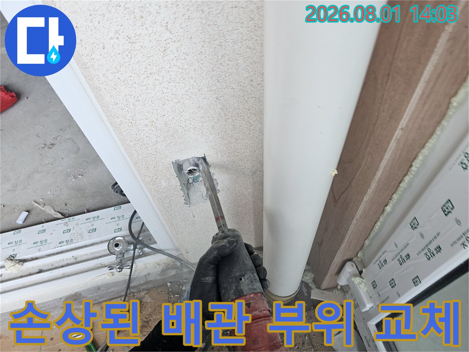 장갑을 낀 손이 세탁실 벽면에서 나온 파이프의 고정 장치와 연결부를 수리하는 모습