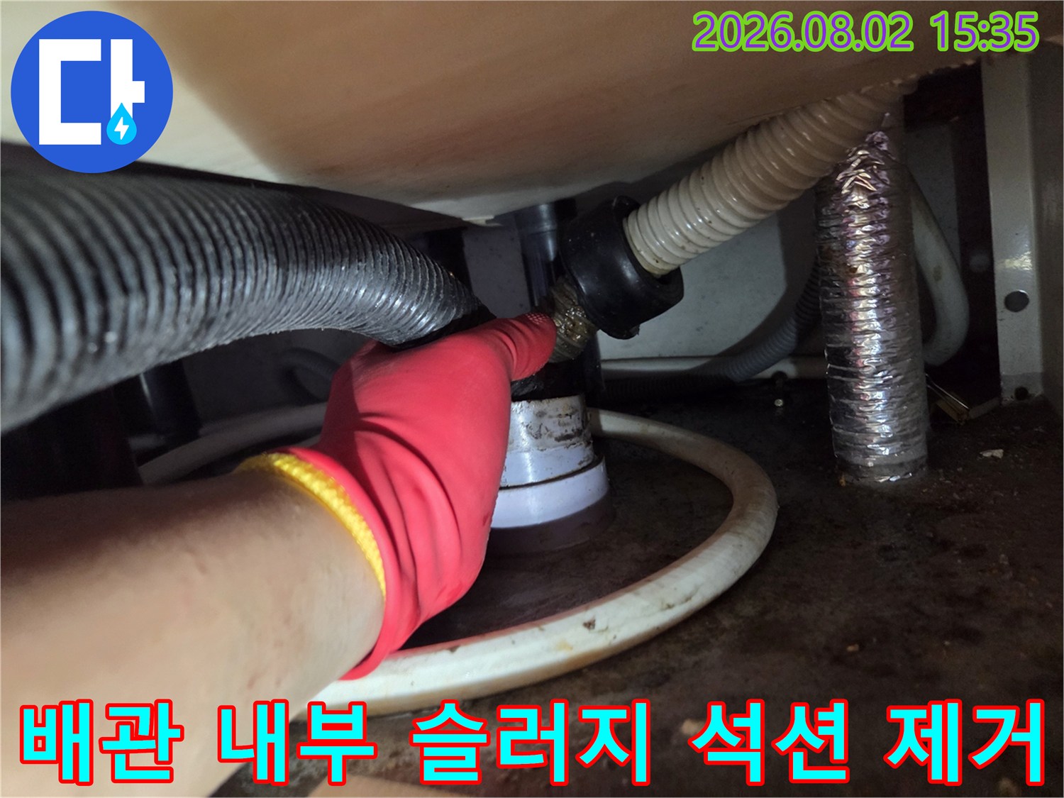 싱크대 하부 배관에 연결된 호스 구간을 석션 장비로 집중 청소하는 장면