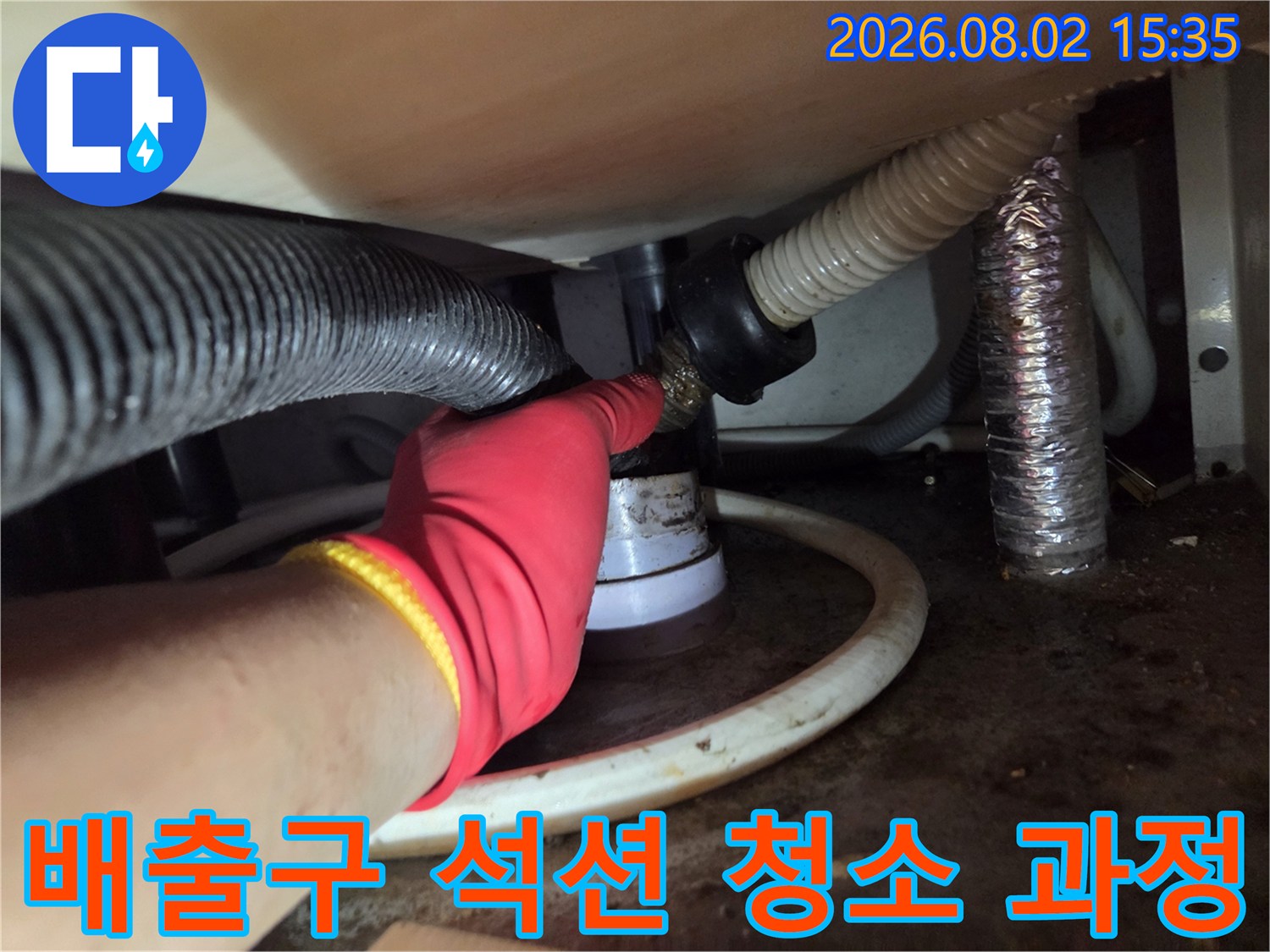 작업자가 장갑을 끼고 싱크대 하단 배수 파이프에 석션 호스를 연결하여 내부 오물을 제거하는 장면
