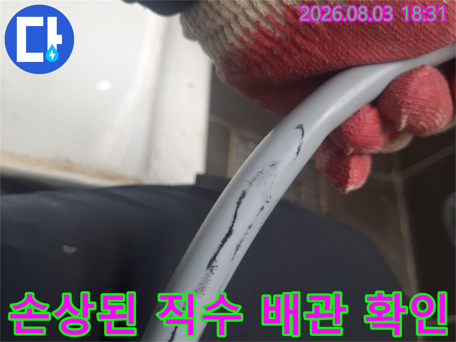 장갑을 낀 손으로 노출된 파손 부위가 있는 회색 직수 배관을 잡고 있는 모습