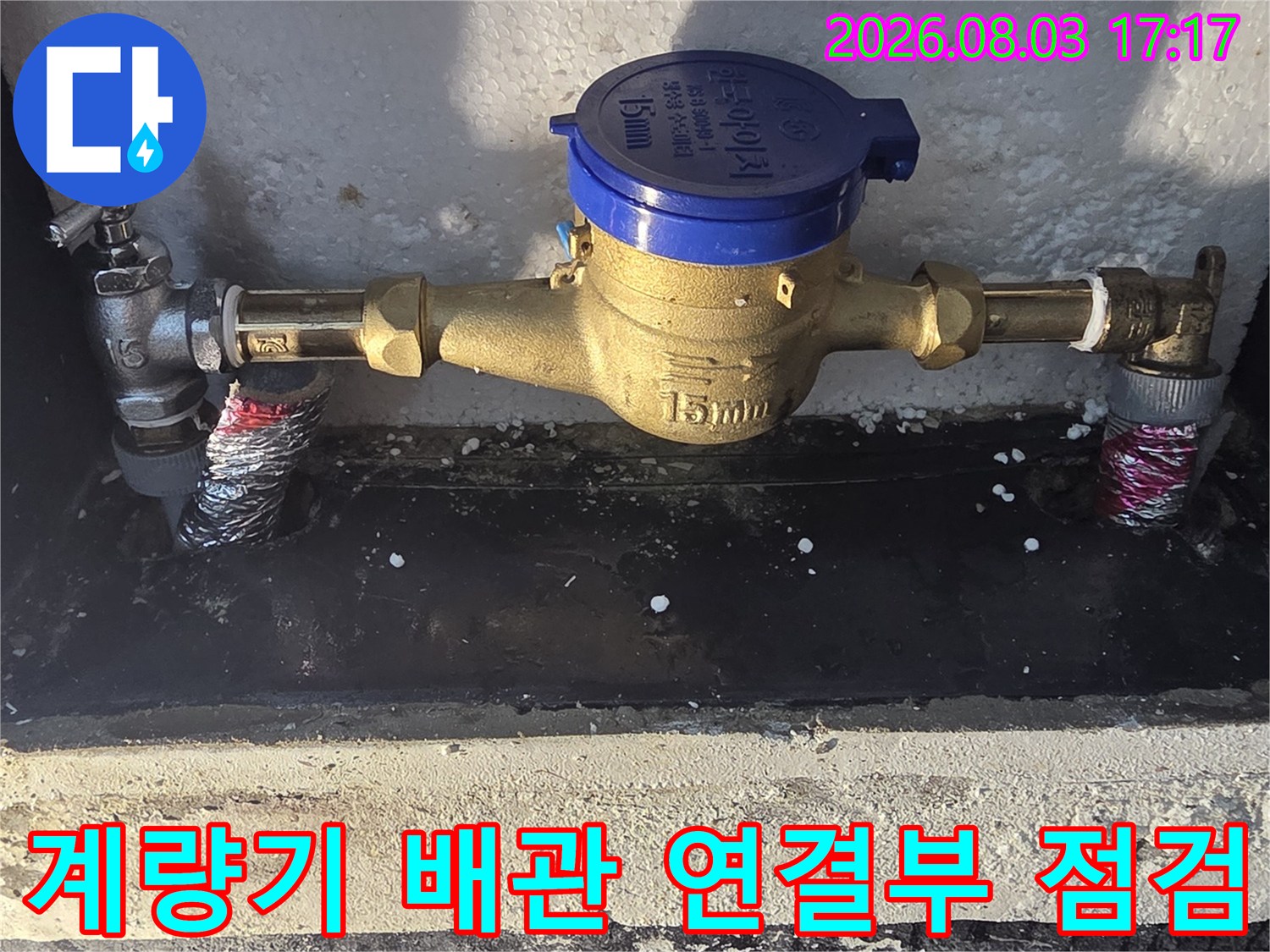 파란색 덮개가 있는 수도 계량기와 노출된 배관 연결 부위