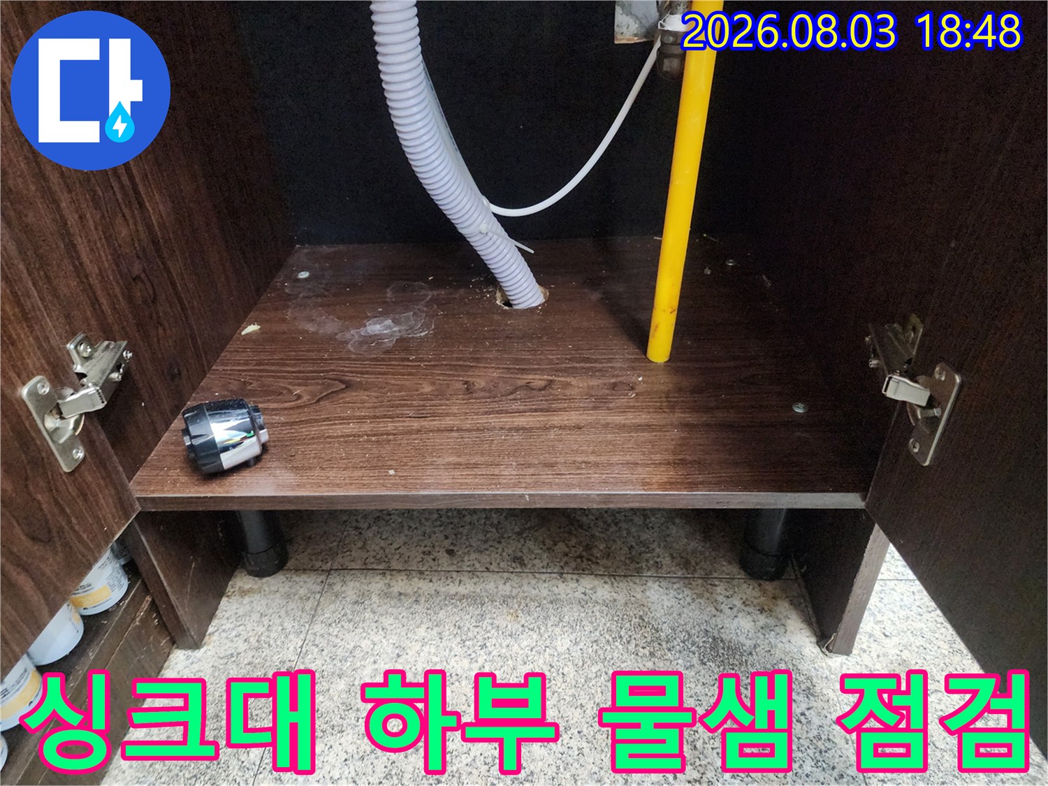 노란색 배관과 흰색 호스가 연결된 싱크대 하단 공간의 누수 정밀 진찰