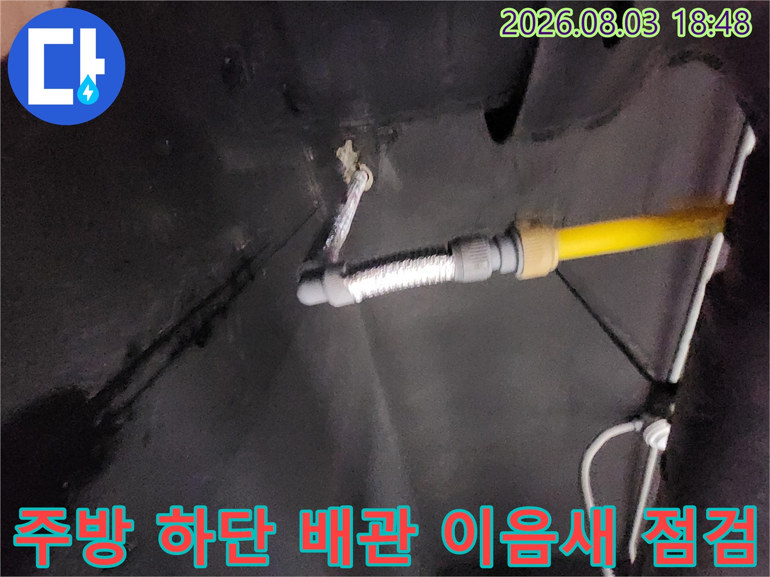 노란색 파이프와 굴곡진 호스가 연결된 배관 부위의 상세 사진