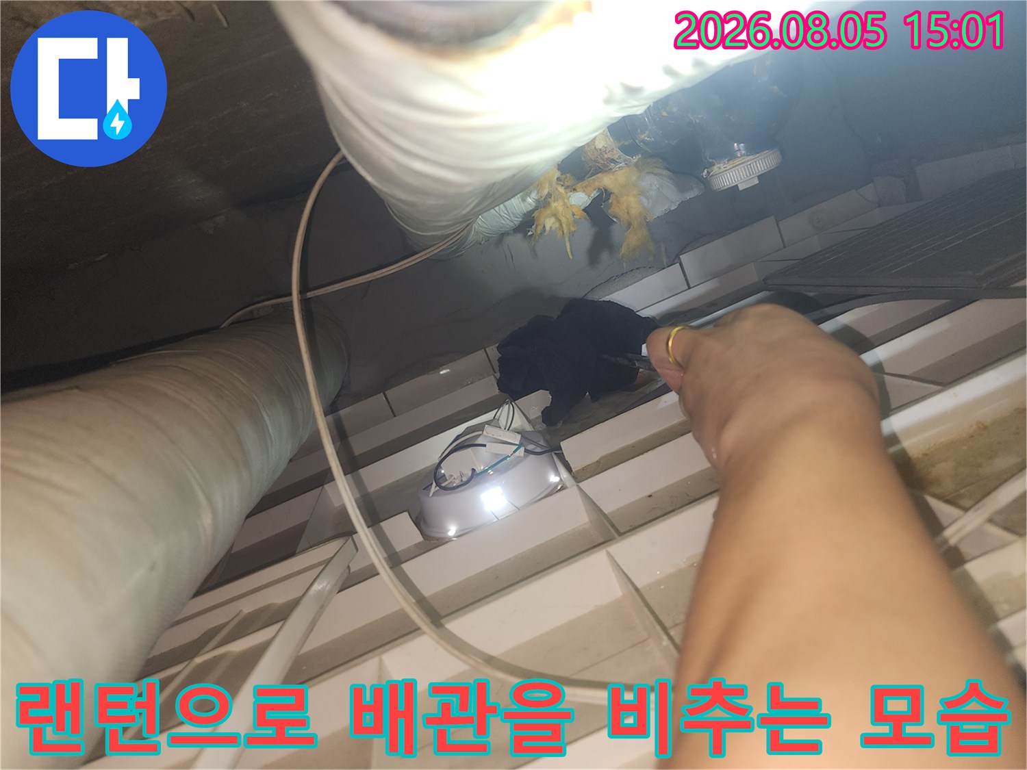 어두운 천장 공간에서 손전등으로 물샘 부위를 정밀하게 살피는 장면