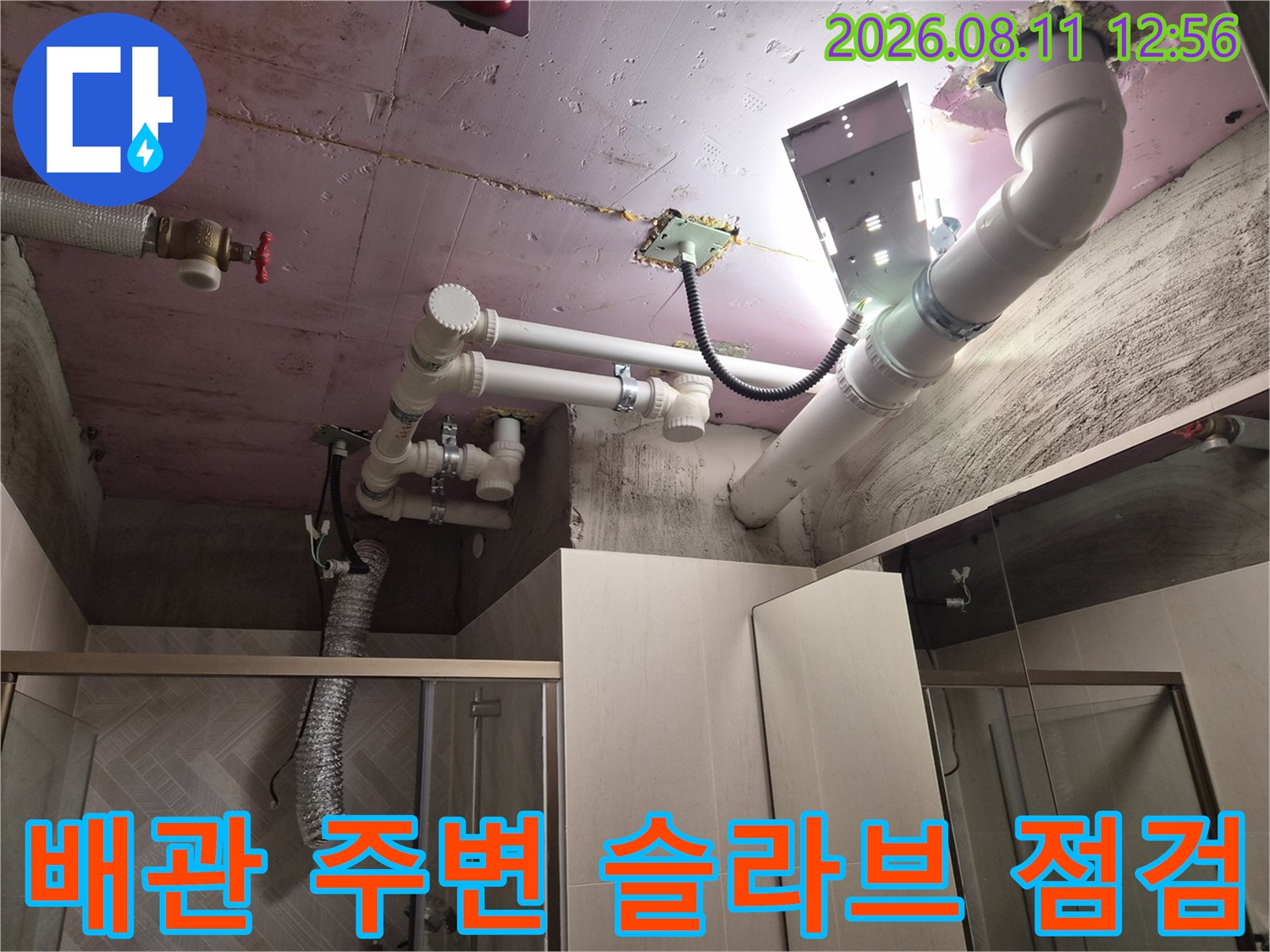 조명을 사용하여 천장 내부 배관과 콘크리트 슬라브의 접합부를 근접 촬영한 사진입니다.