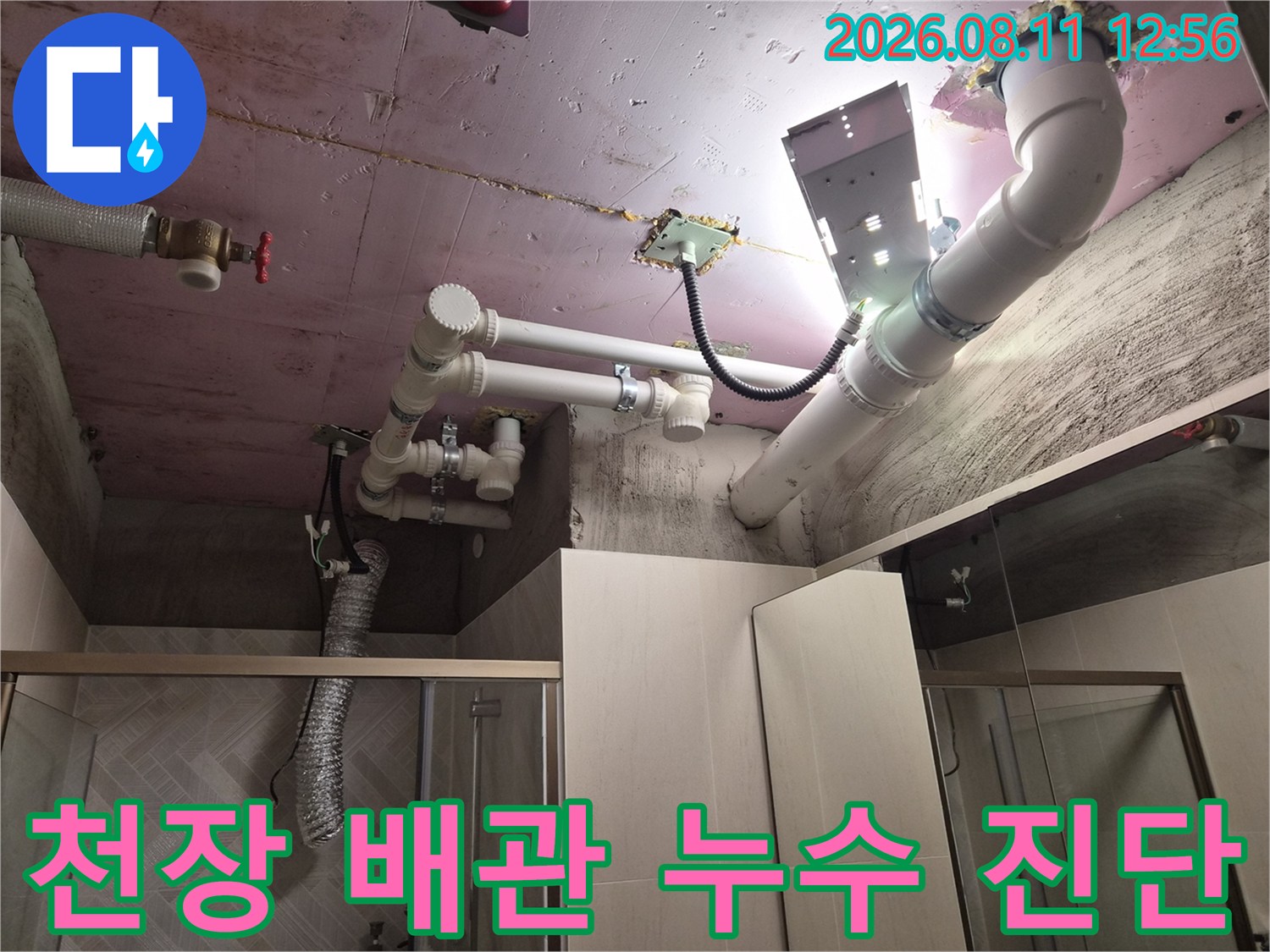 조명을 사용하여 천장 내부 배관의 연결 부위를 점검하는 모습입니다.