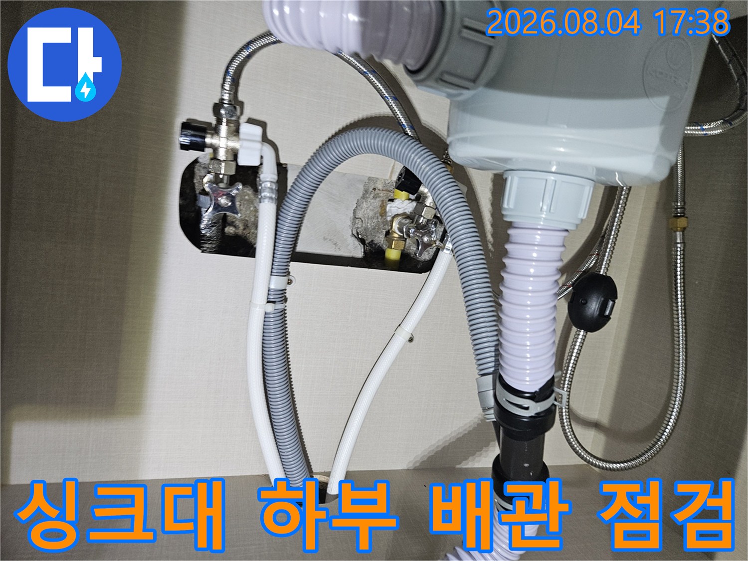 싱크대 아래쪽 연결된 회색 유연한 배관과 수도 밸브를 점검하는 모습