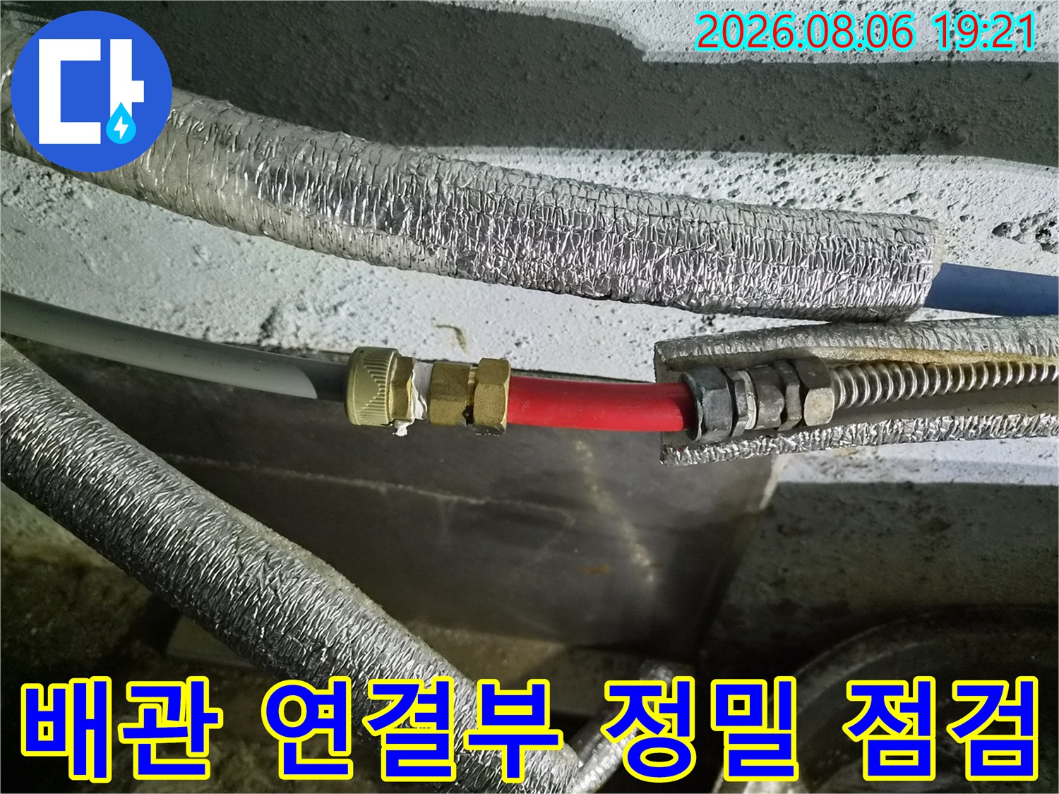 금속 밸브와 빨간색 호스가 체결된 배관 구간의 상세 사진