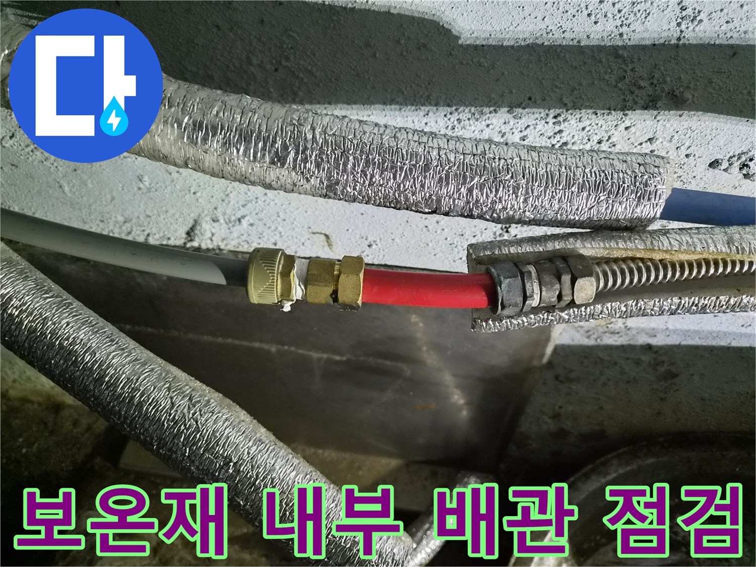 은박 보온재가 씌워진 배관의 빨간색 연결 부위를 집중적으로 보고 있습니다.