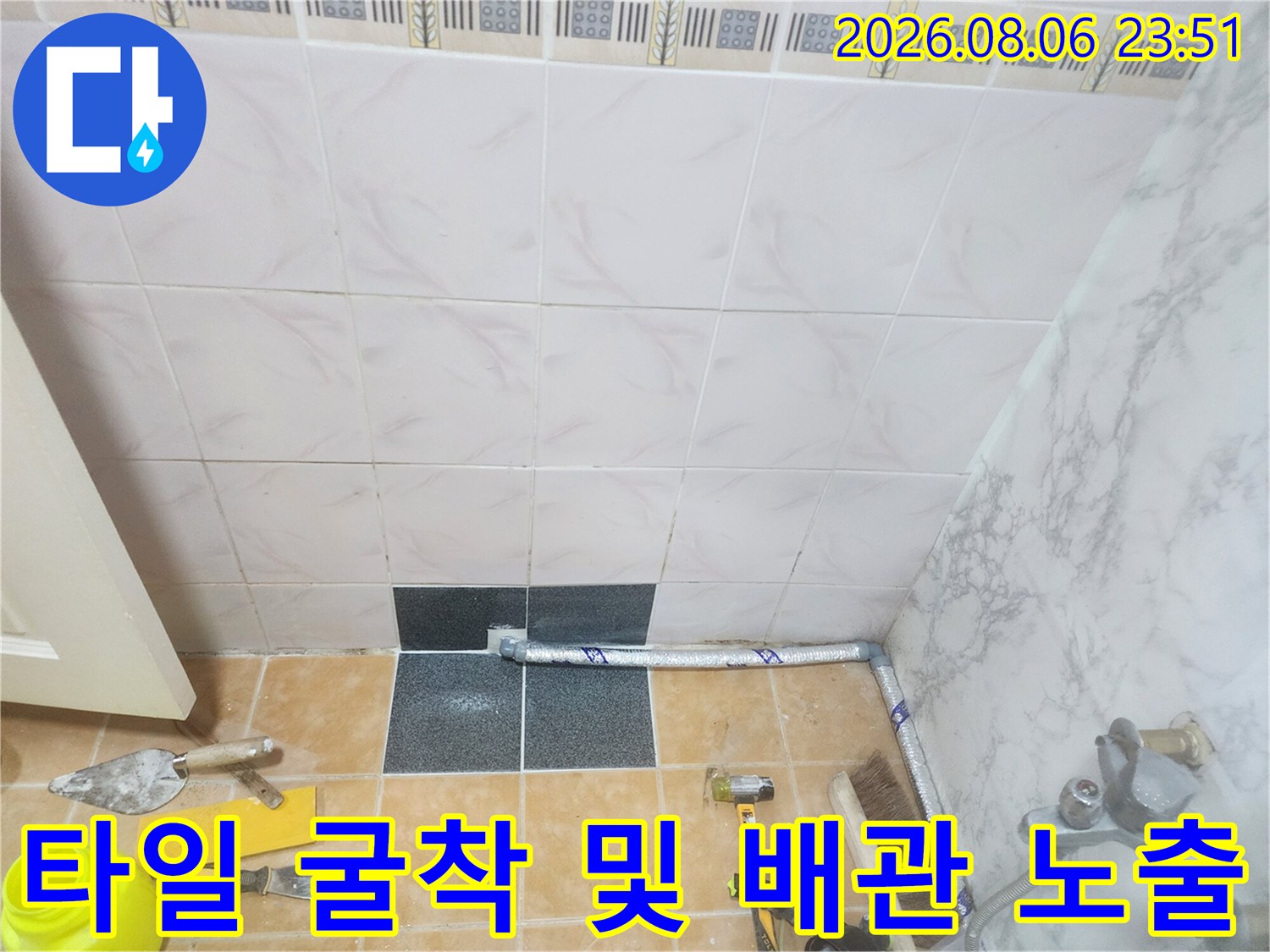 누수 지점 확인을 위해 타일을 제거하고 배관이 드러난 공사 현장 사진입니다.