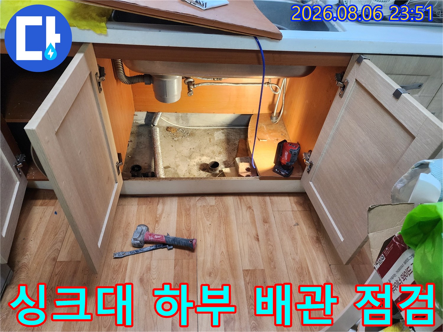 중랑구 면목동 싱크대 하부장 내부의 노출된 배관과 작업 도구 모습