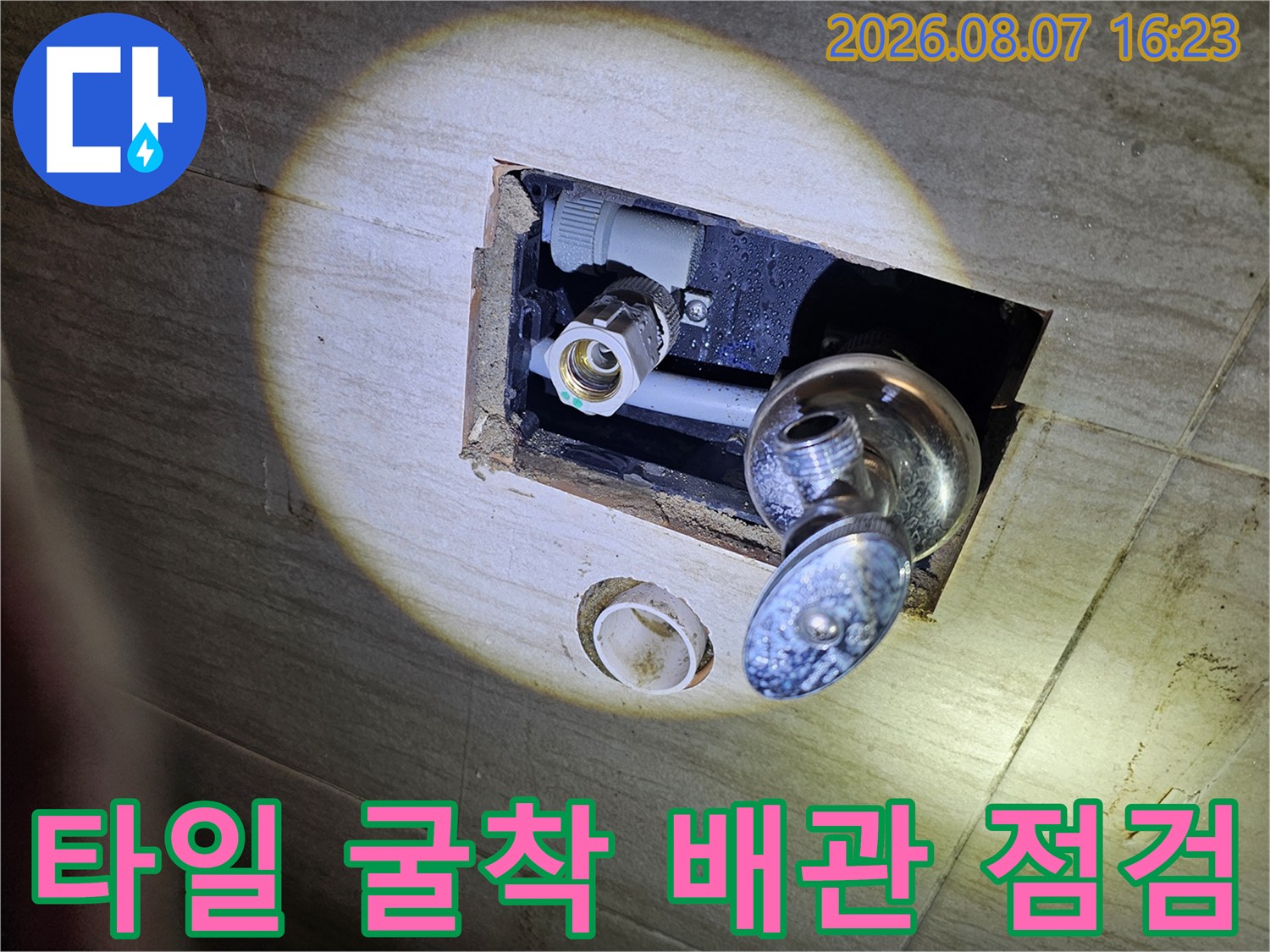 세면대 하단 벽면 - 노출된 회색 급수 배관과 수전 연결부