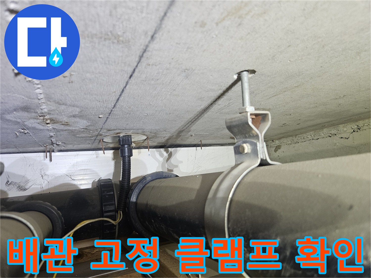 천장 배관을 지지하는 금속 부품과 검은색 하수관의 근접 촬영