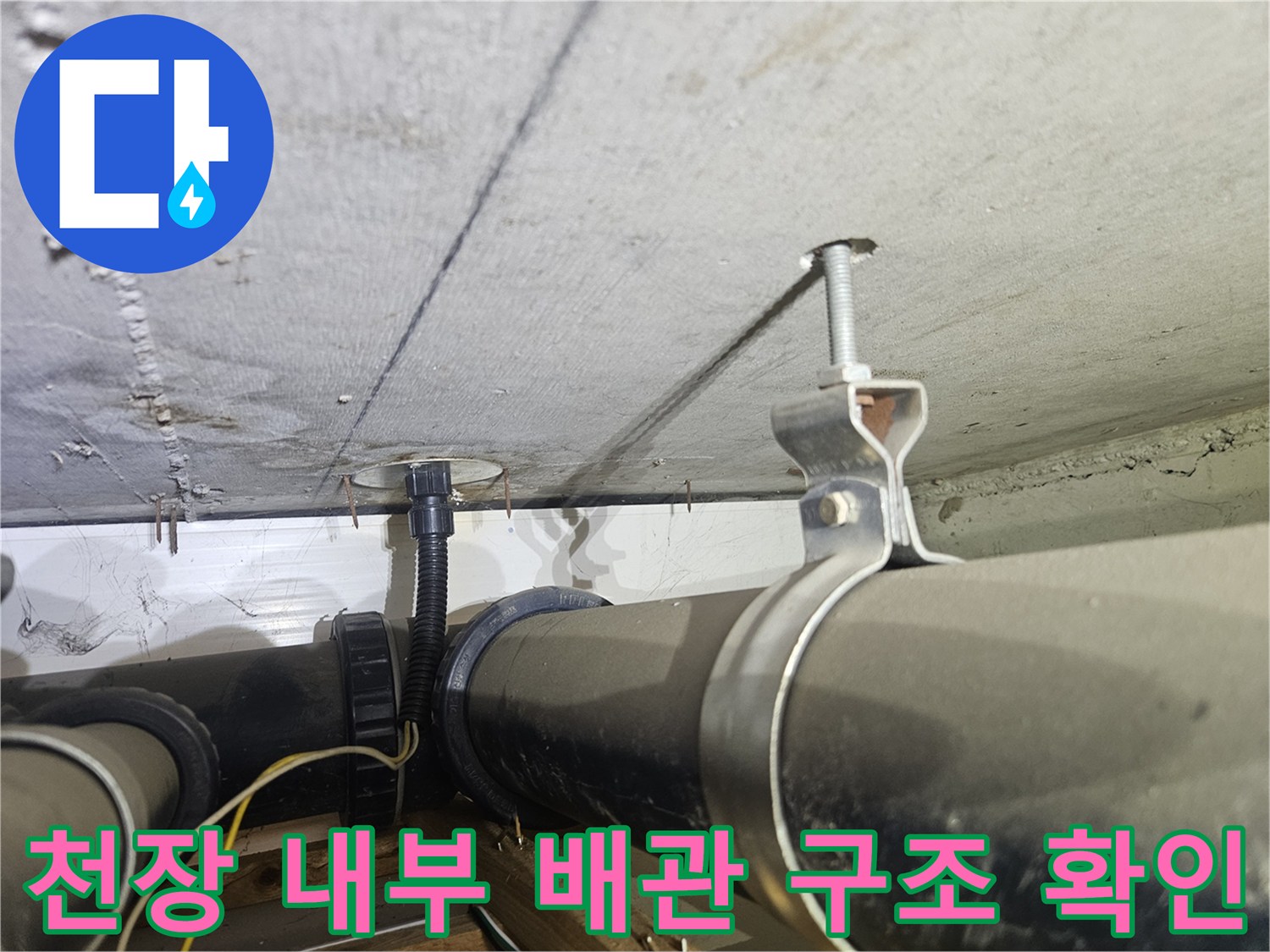 천장에 고정된 검은색 하수관과 금속 나사산 장치 촬영