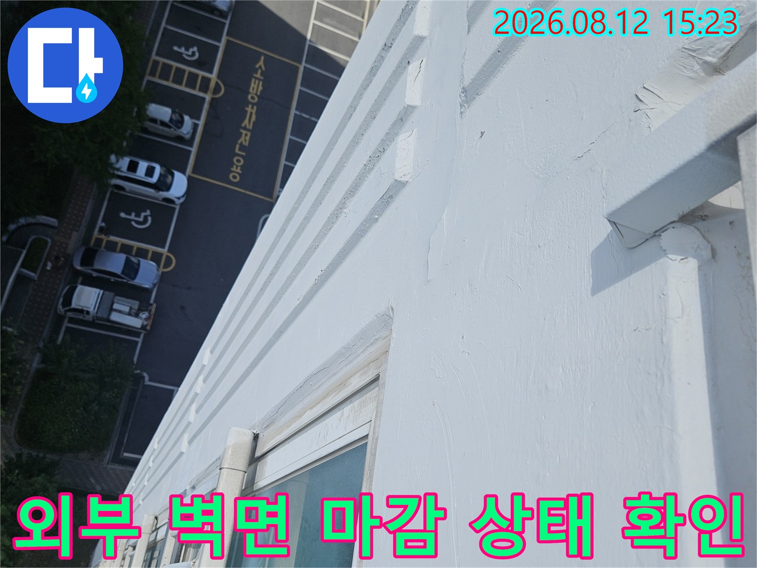 흰색 외벽 도장면과 창문 프레임-하단 주차장 전경이 함께 찍힌 사진