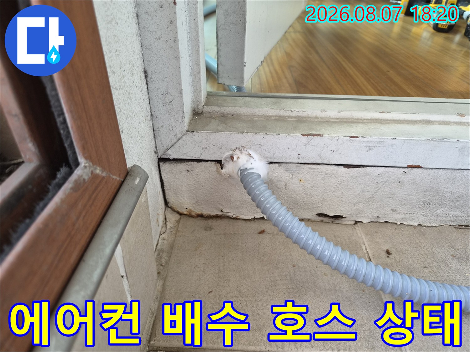 창틀 아래로 연결된 에어컨 드레인 배수 호스의 모습입니다.
