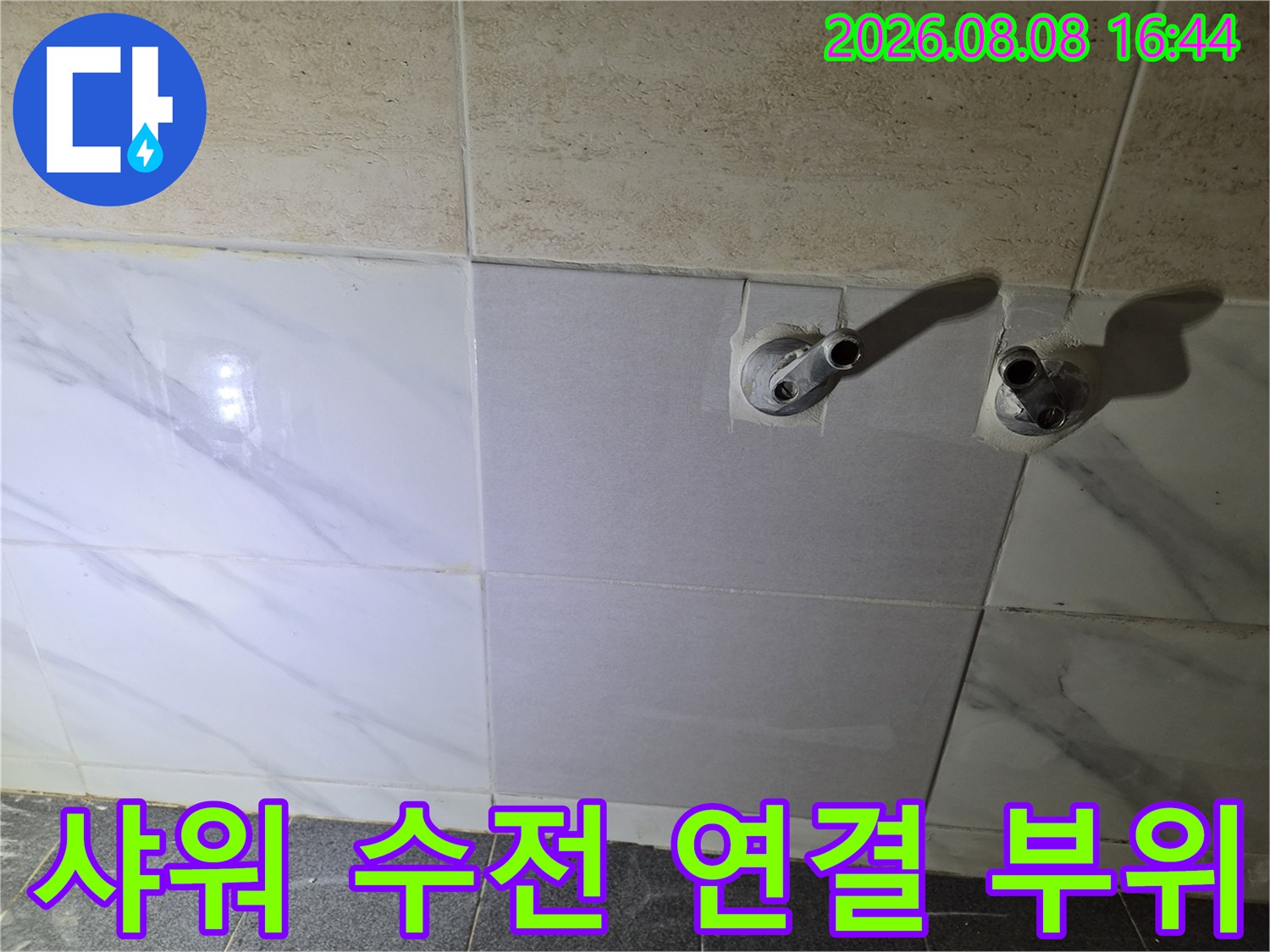 화장실 타일 벽면에 노출된 샤워기 배관과 연결 부속의 상세 사진입니다.