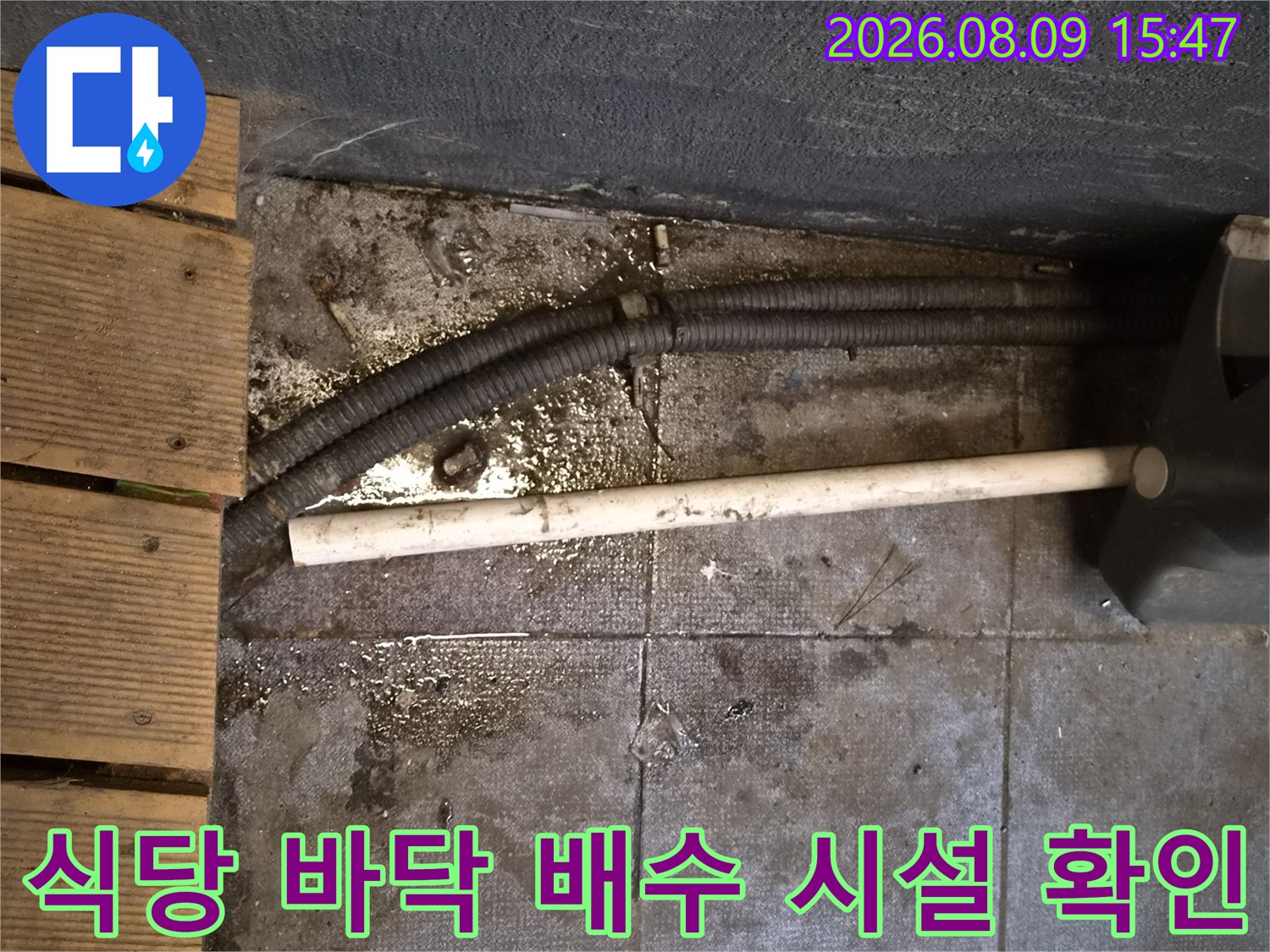 상가 식당의 노출된 드레인과 주변 타일의 습기 상태를 보여줍니다.