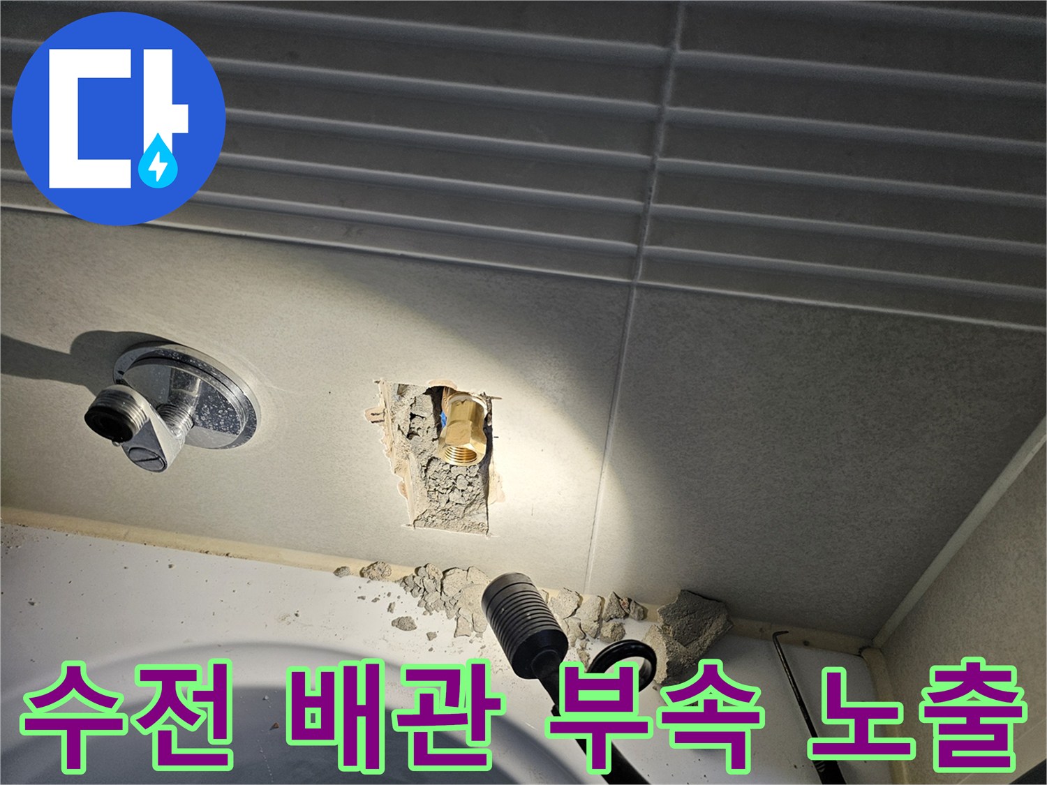화장실 수전 아래쪽 타일을 파쇄하여 드러난 금속 배관 부속품