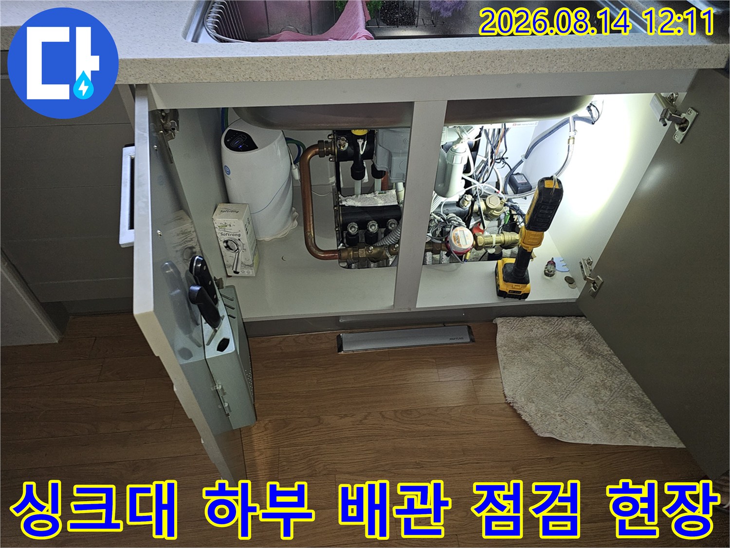 싱기대 하부장 내부의 복잡한 수도 배관과 계량기 상태 확인