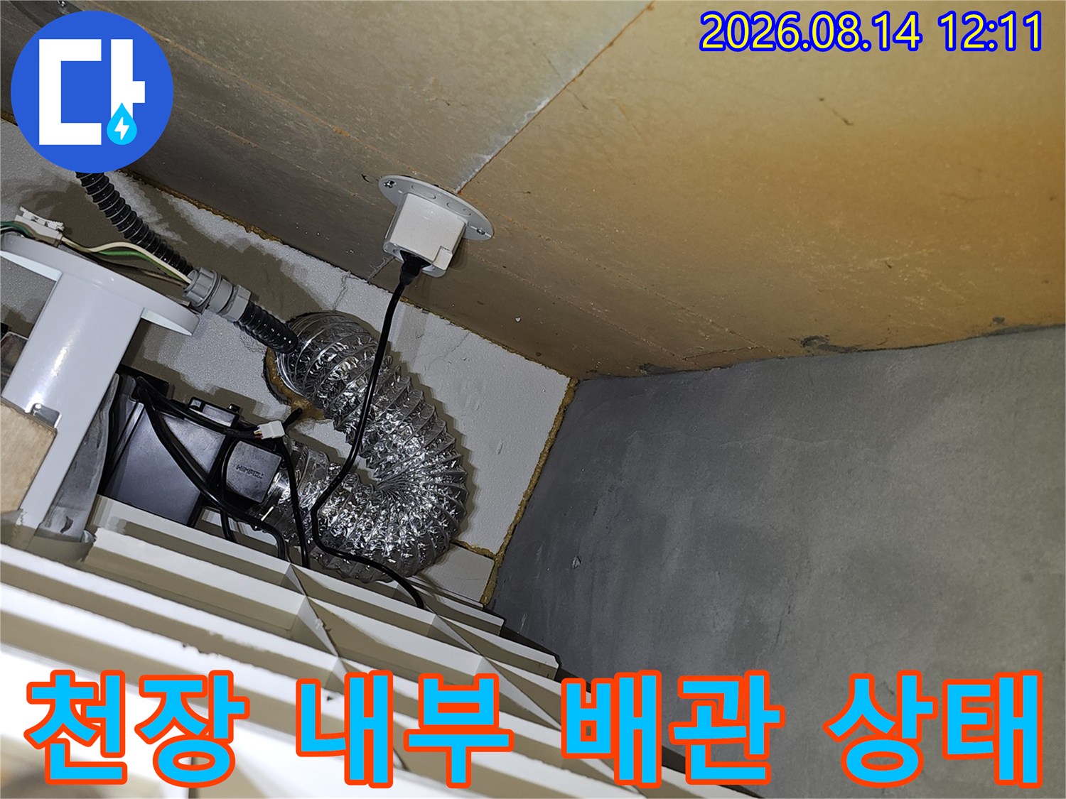 아파트 천장 내부의 굴곡진 주름관과 배관 연결 부위를 근접 촬영한 사진입니다.