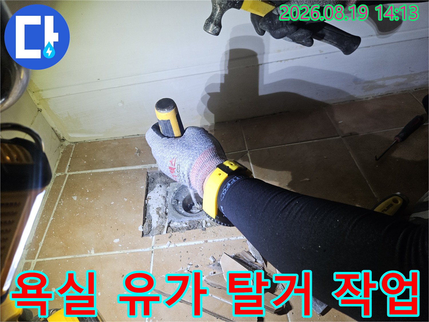 배수구 주변 타일을 정리하고 하수관을 노출시킨 공사 진행 사진입니다.
