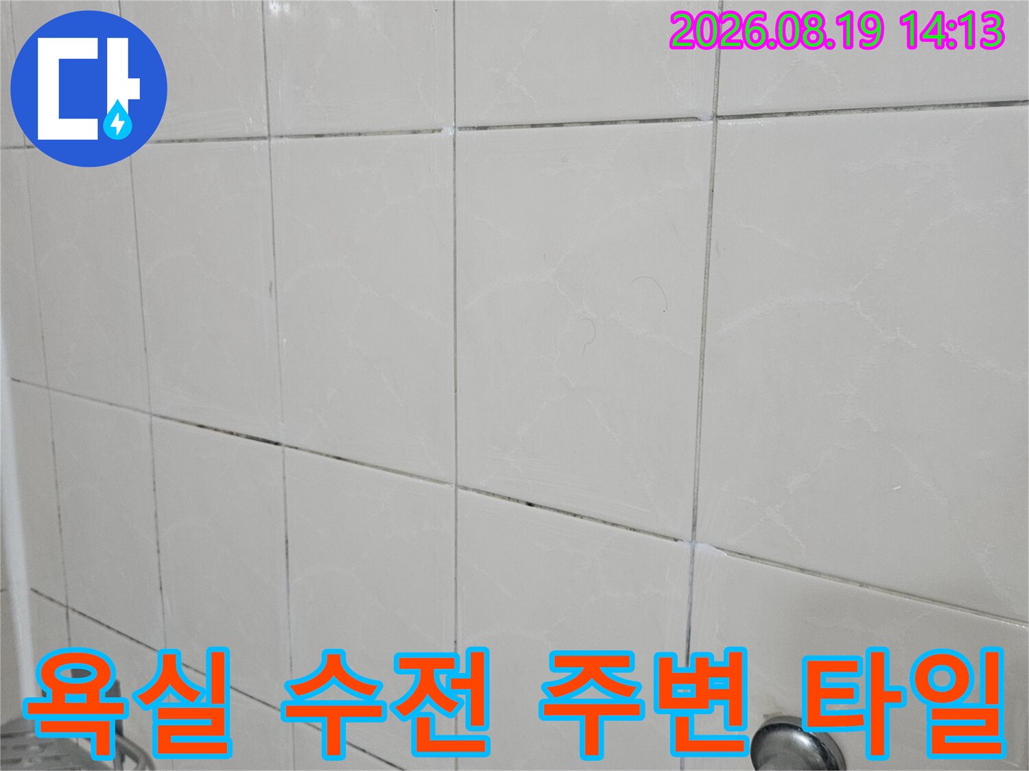욕실 벽면의 밝은 타일과 수전 기구가 찍힌 사진입니다.
