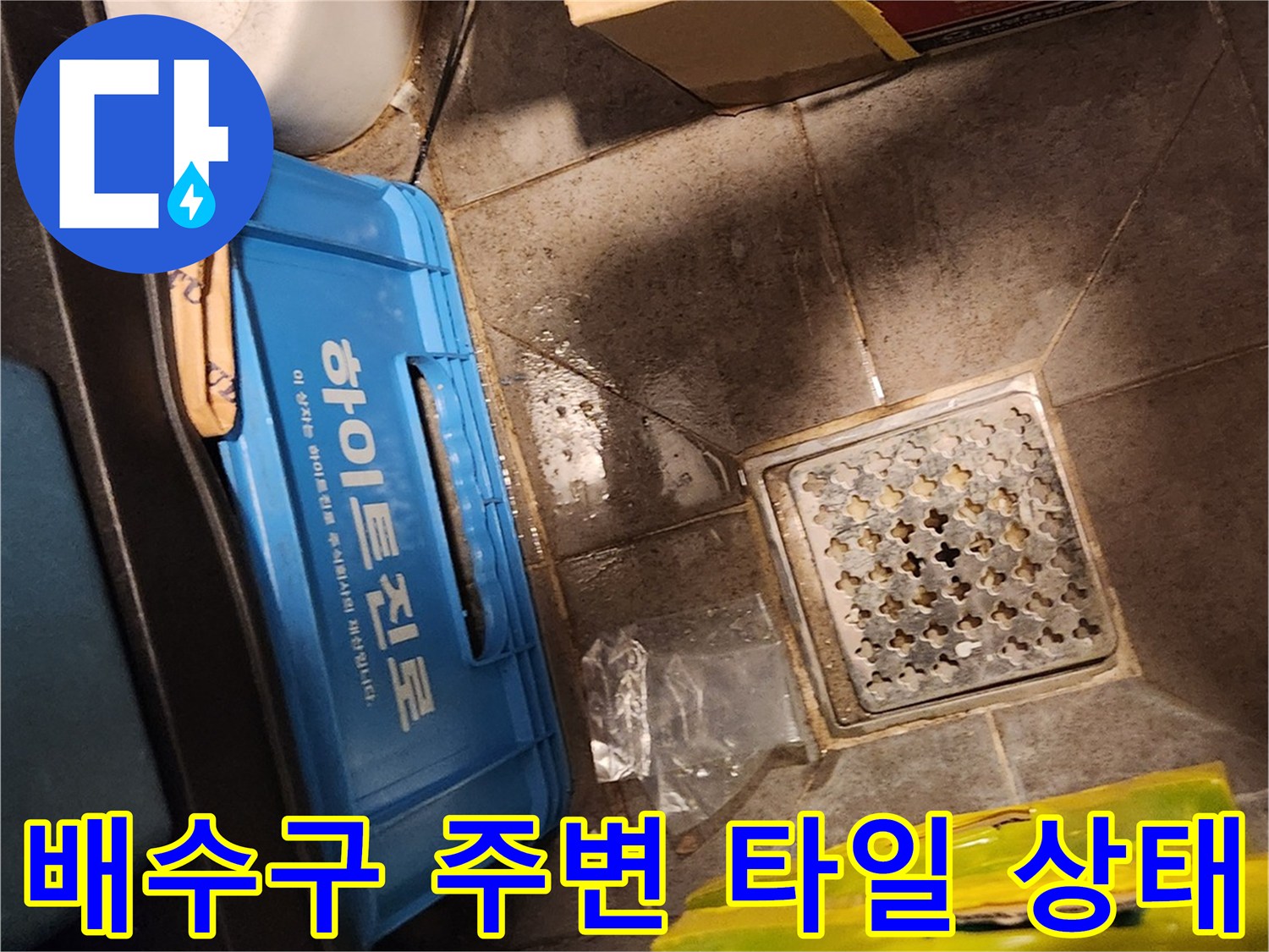 창고 내부 배수구 주변의 축축한 타일 표면과 적재된 물건들