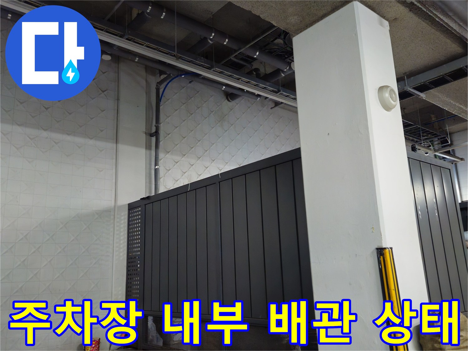 지하 주차장 천장의 노출된 배관과 기둥의 모습