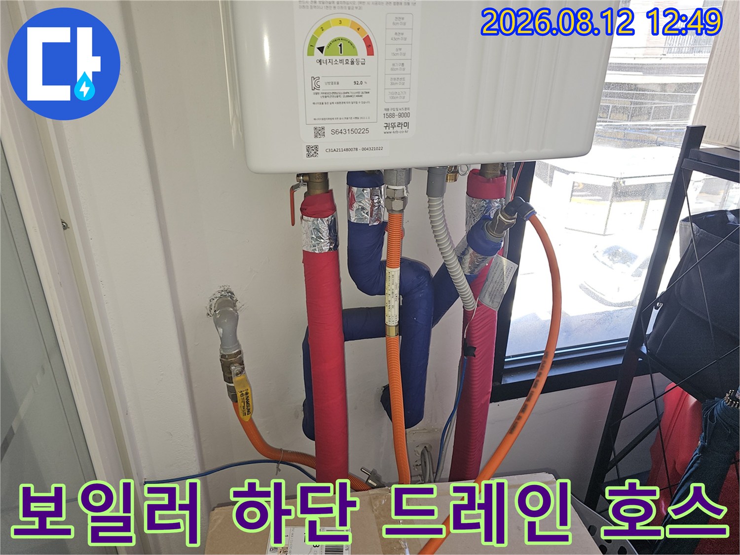 주황색 드레인 호스가 보일러 아래쪽으로 연결된 상세 모습입니다.