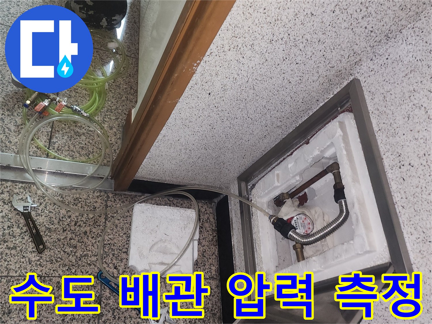 점검구 안쪽 배관에 연결된 공압 장비와 압력 게이지의 근접 촬영