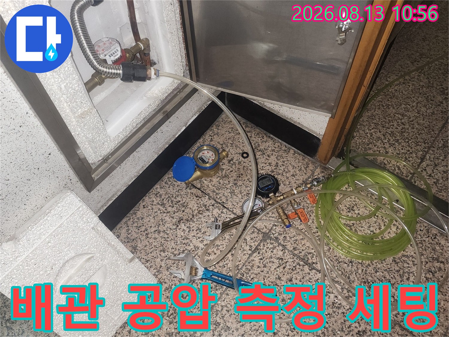 흰색 점검함 내부 배관에 연결된 투명 호스와 게이지-작업 도구들