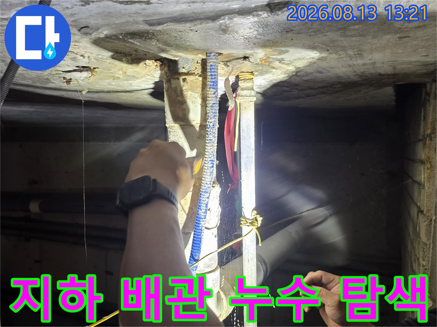손전등 조명을 사용하여 배관 주변의 오염된 부위를 정밀하게 조사하는 모습입니다.