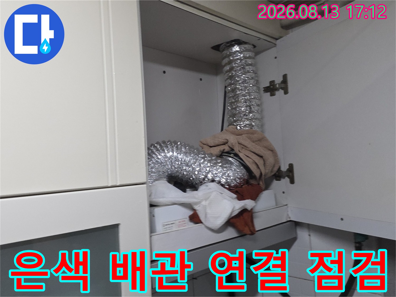 싱크대 상부장 뒤편 은색 자재로 감싸진 굴곡진 배관 모습