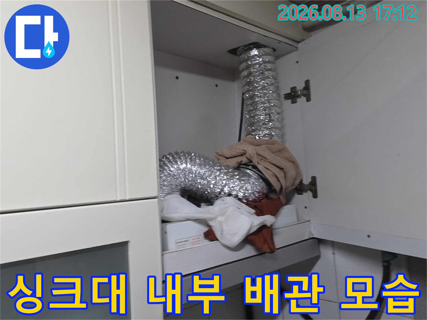 싱크대 하부장 안쪽 은색 자재로 된 굴곡진 배관