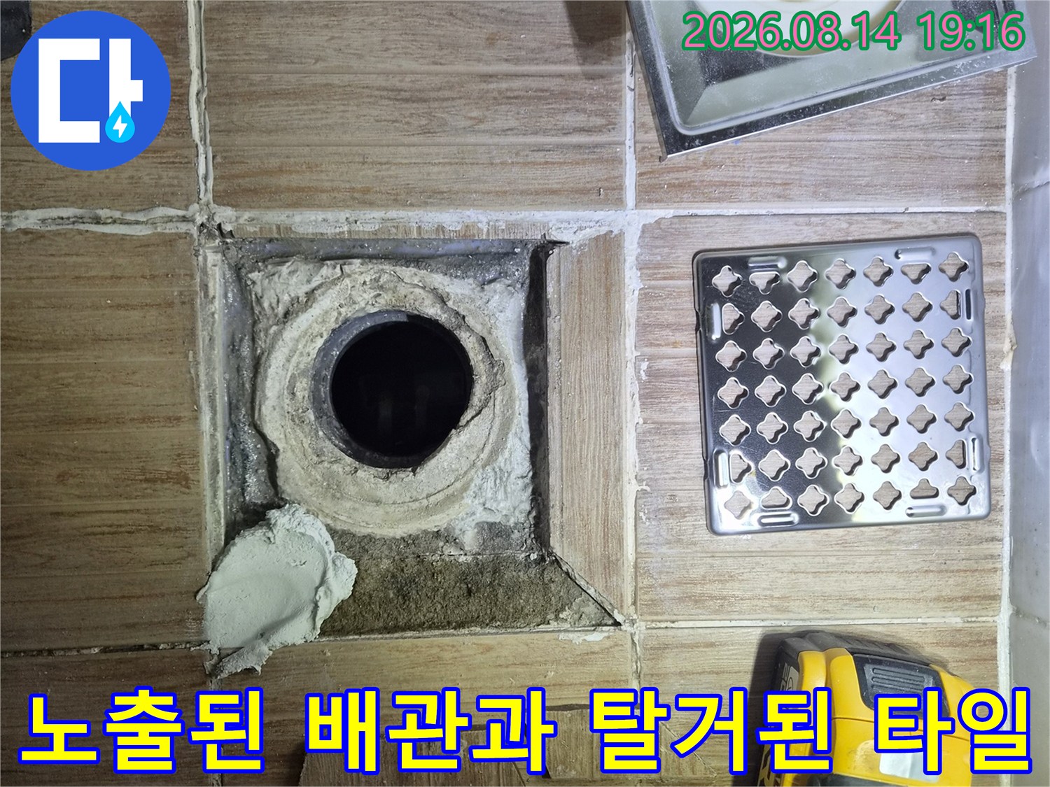 공사 중인 화장실-배수구 주변의 파손된 타일과 노출 배관입니다.