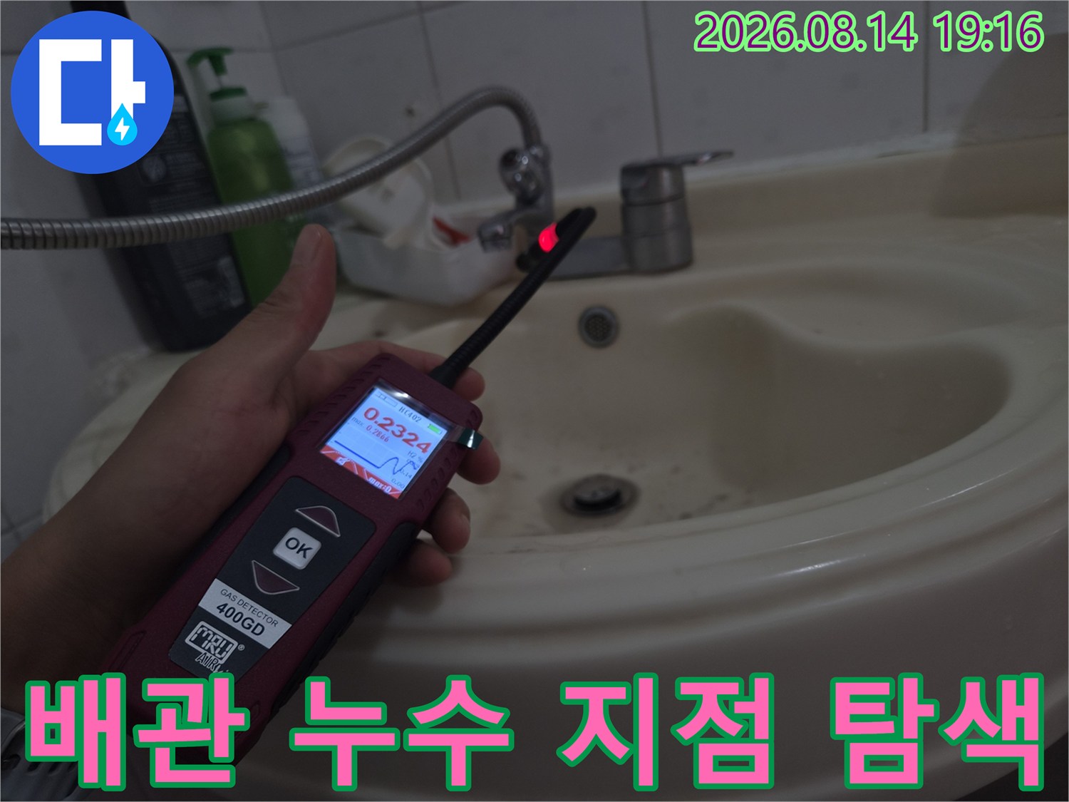 숫자가 표시된 가스 탐지기를 들고 세면대 주변 배관을 검사하고 있습니다.