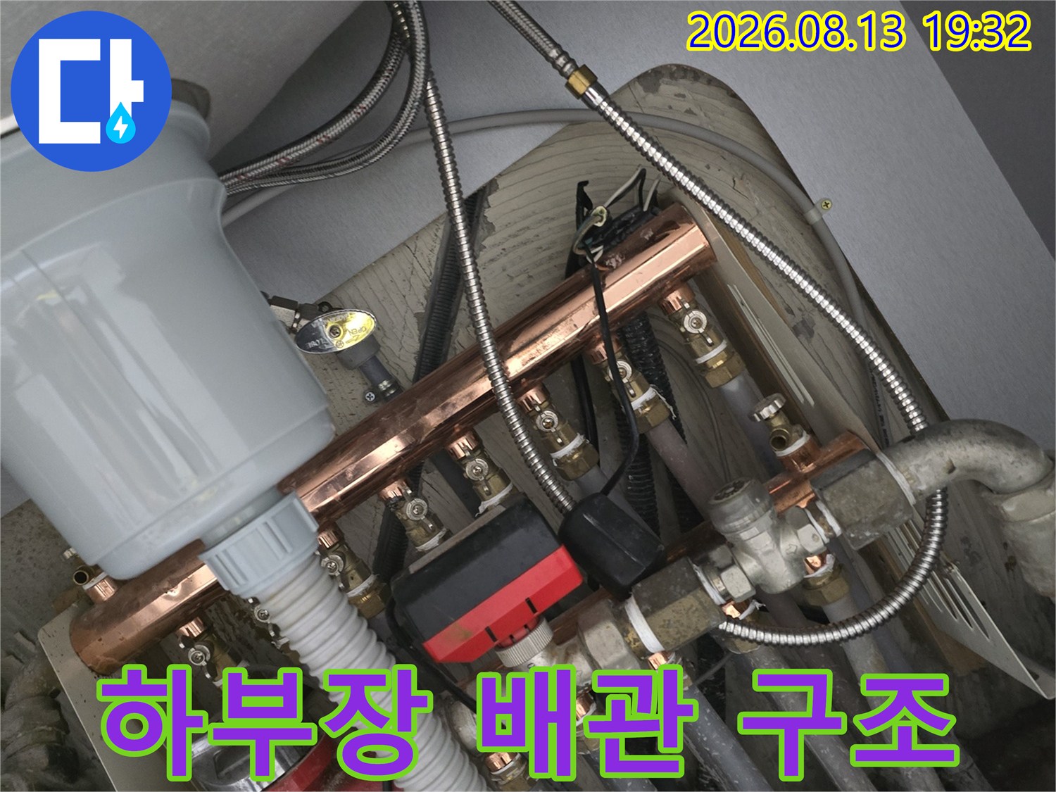 싱크대 하부장 내부의 금속 분배기와 급수 호스 연결 부위 상세