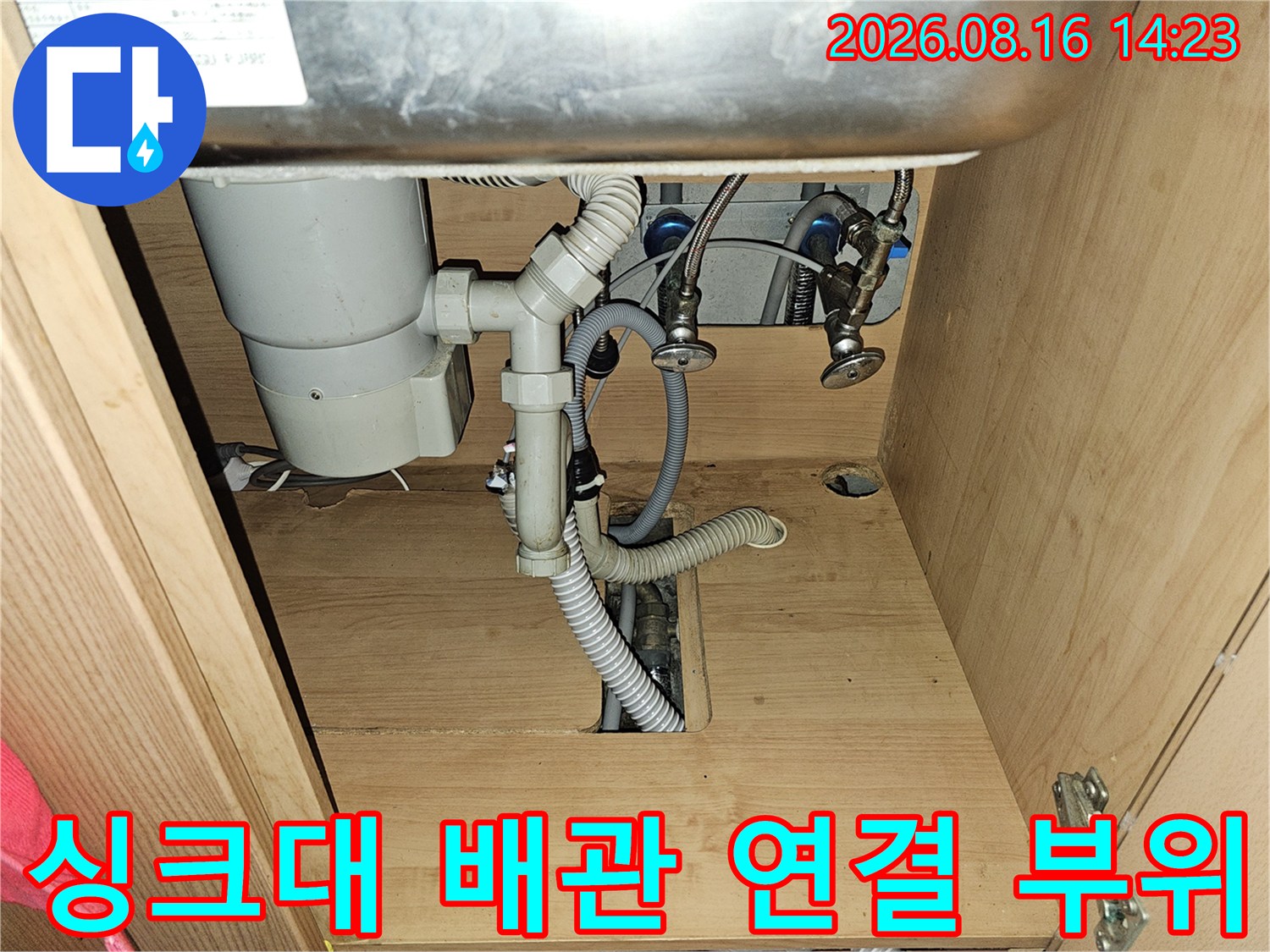 싱크대 하부장 내부의 흰색 배수 관로와 연결 지점
