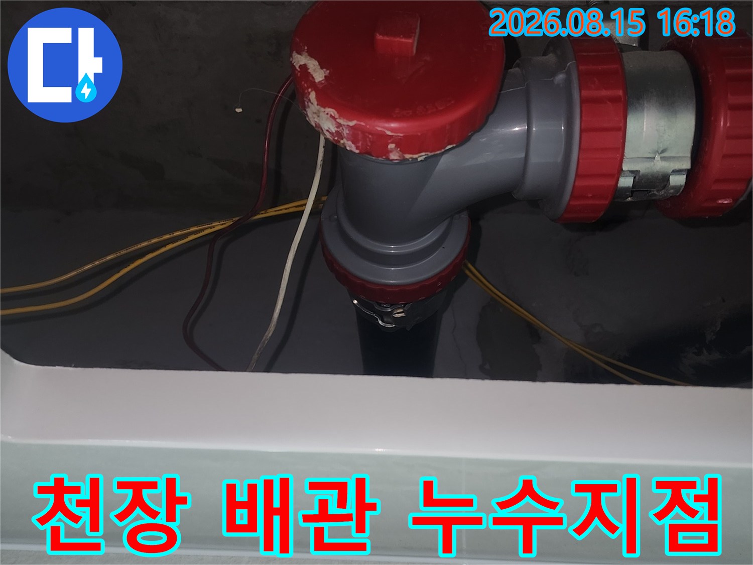화장실 천장 내부의 붉은색 소재구와 회색 배관 연결부