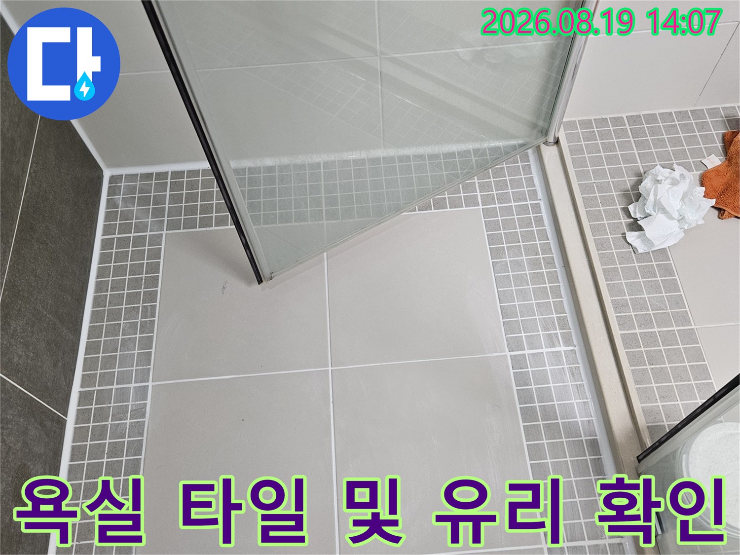 그레이 패턴 타일과 투명한 욕실 파티션의 결합 부위